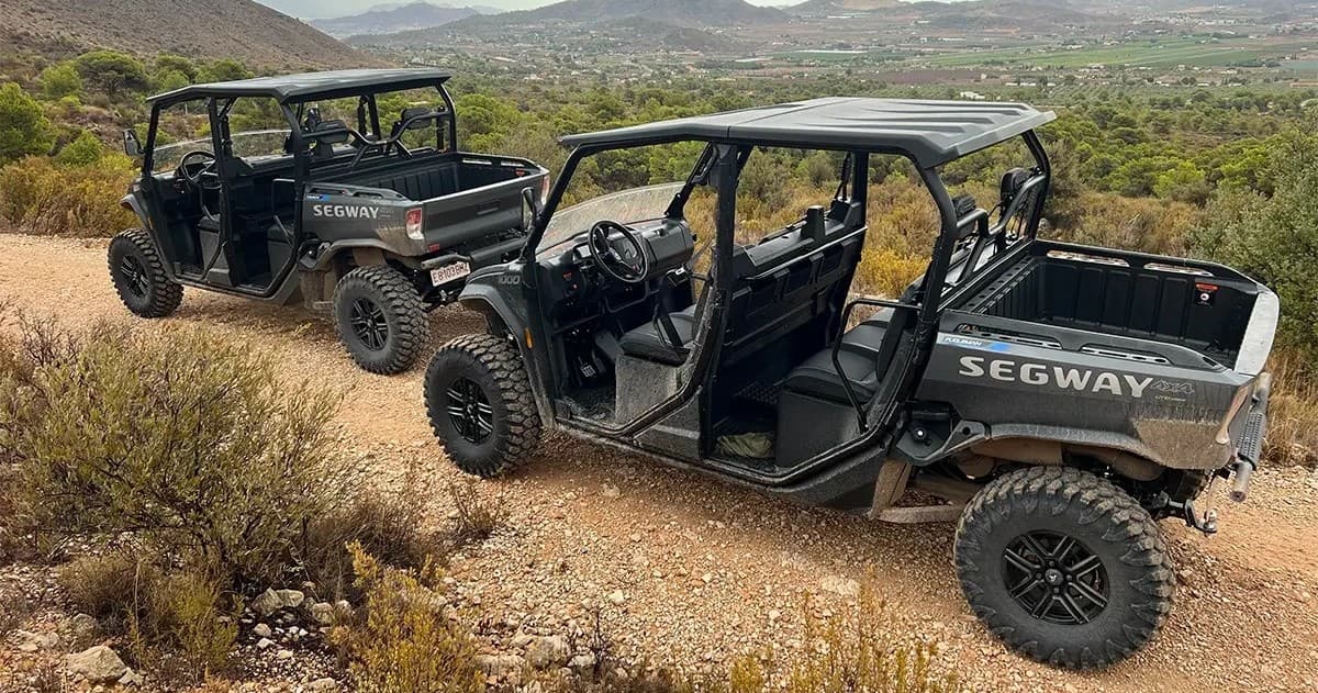 Off-road UTVs on rugged hillside trail overlooking valley