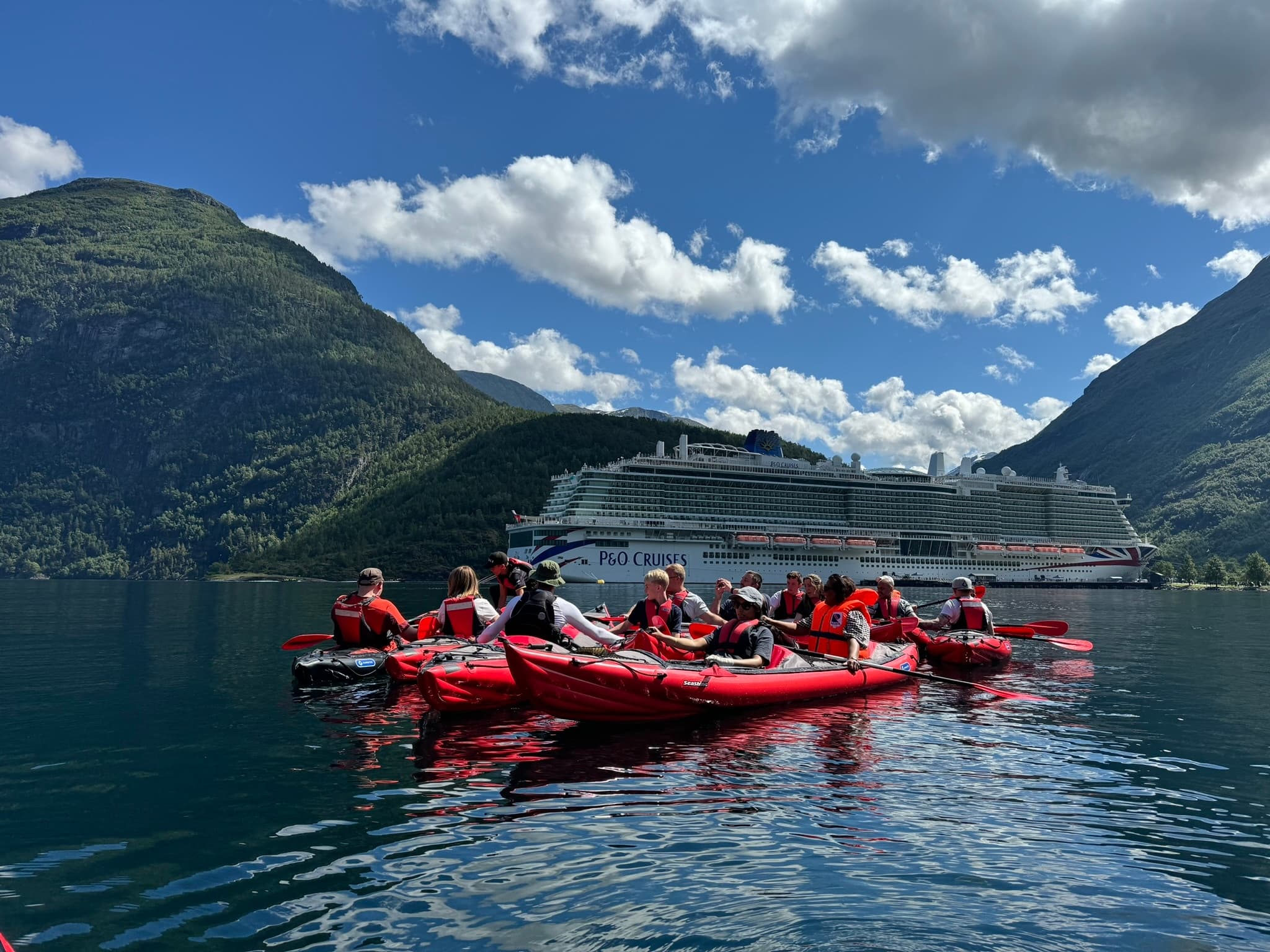 Guided group kayaking near cruise ship in scenic fjord
