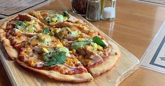 Wood-fired flatbread pizza on wooden board in rustic cafe
