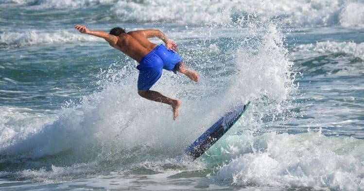 Surfer launching aerial trick over breaking wave in Hawaii ocean