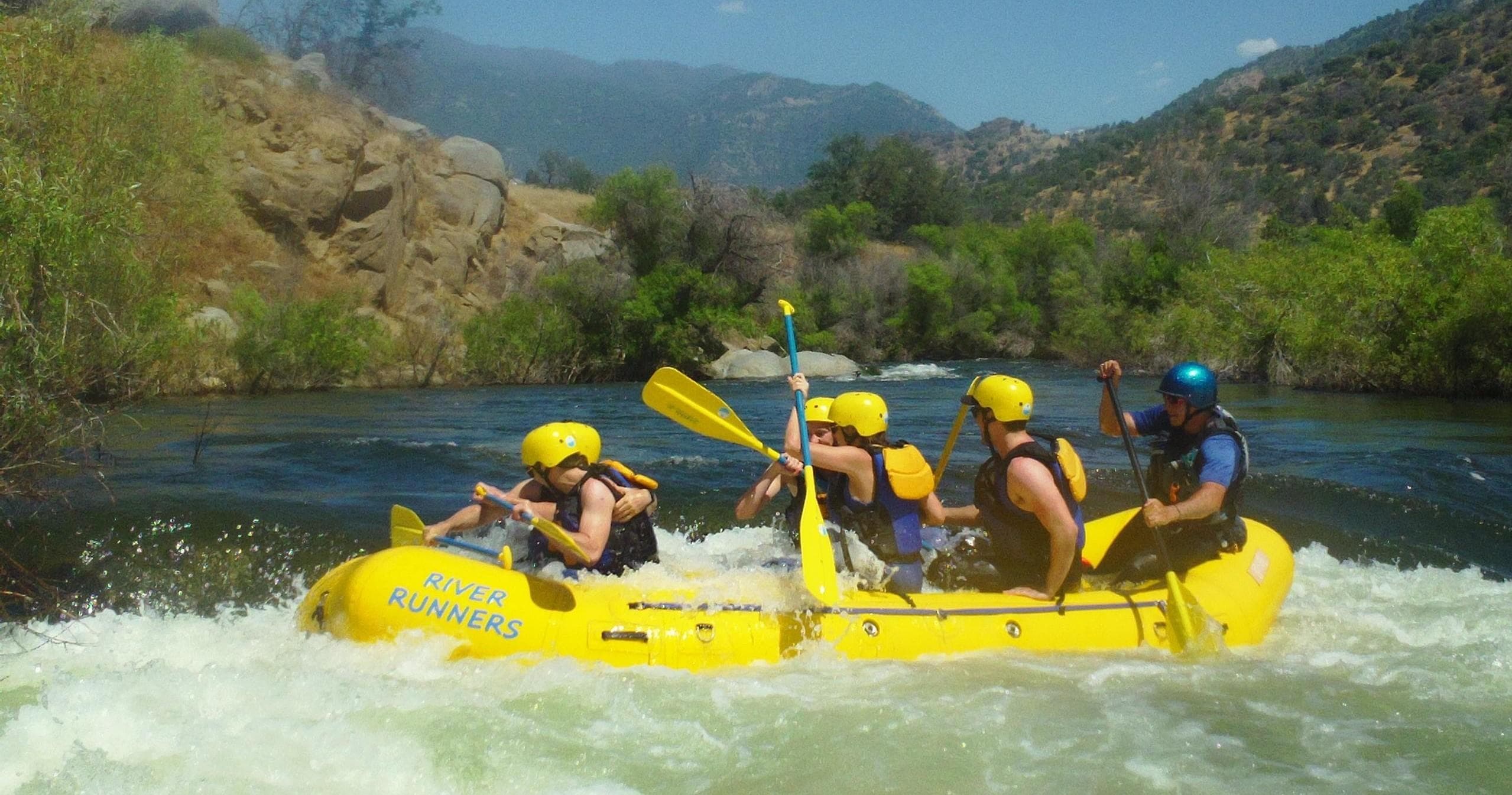 Yellow raft paddlers enjoying mellow rapids in mountain river