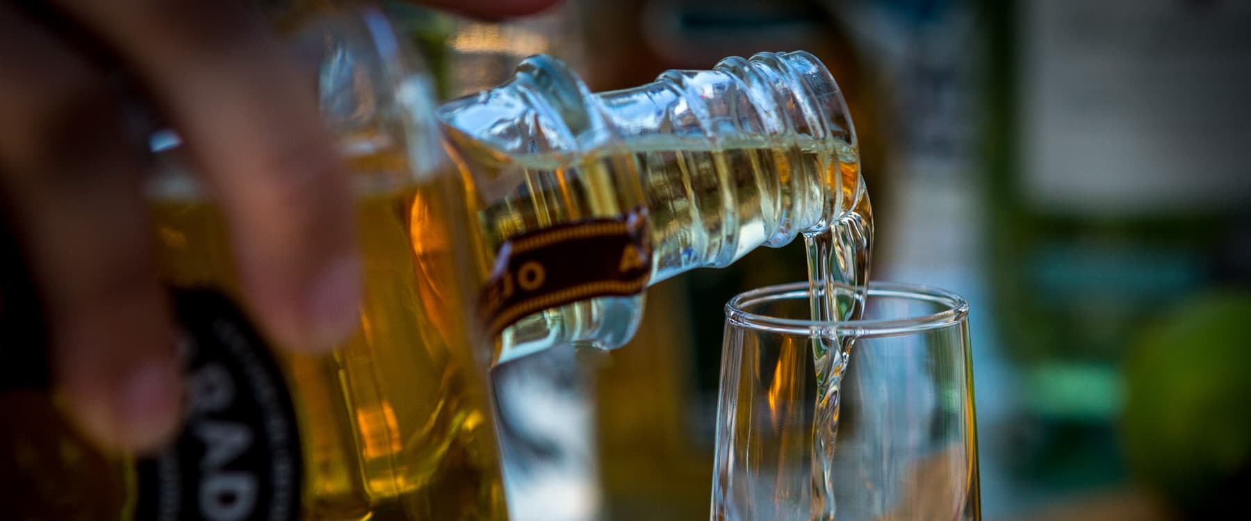 Bartender pouring tequila shot into glass at tasting bar