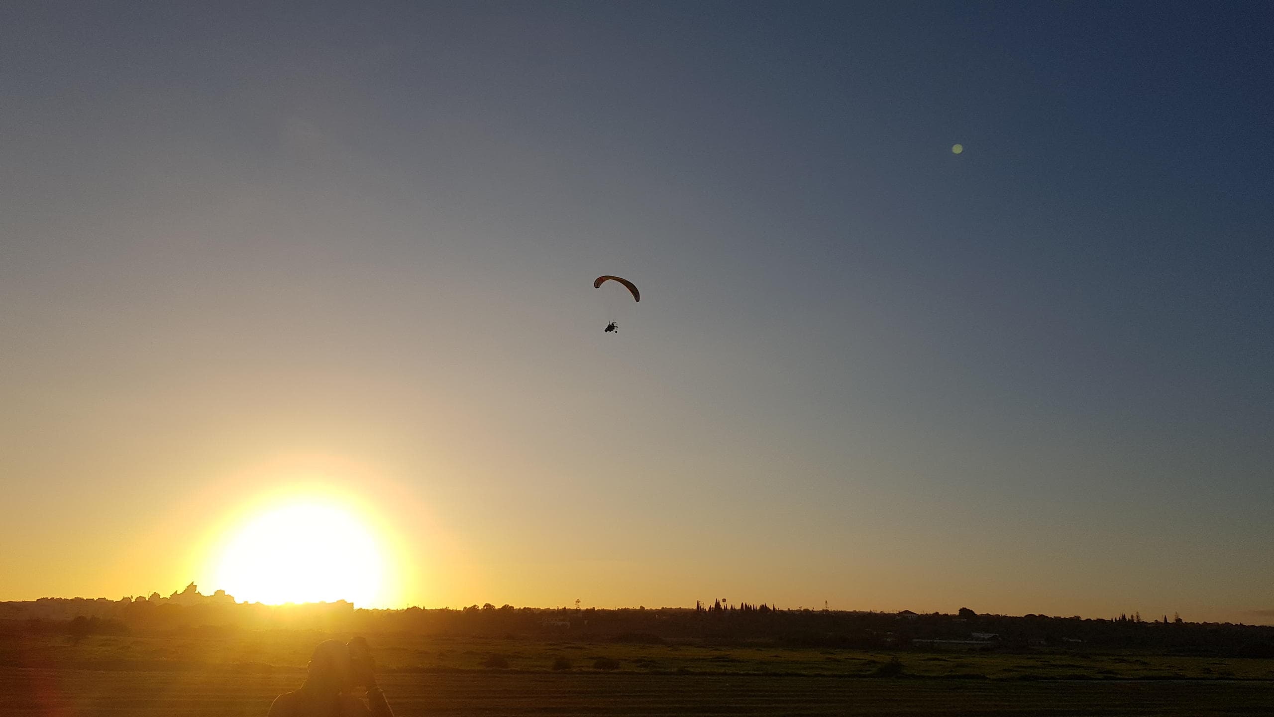 Sunset paraglider silhouette over Algarve horizon and fields