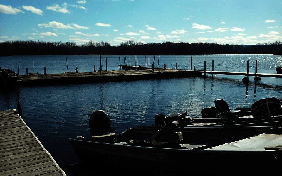 Fishing boats docked at sunrise on a calm lake waterfront