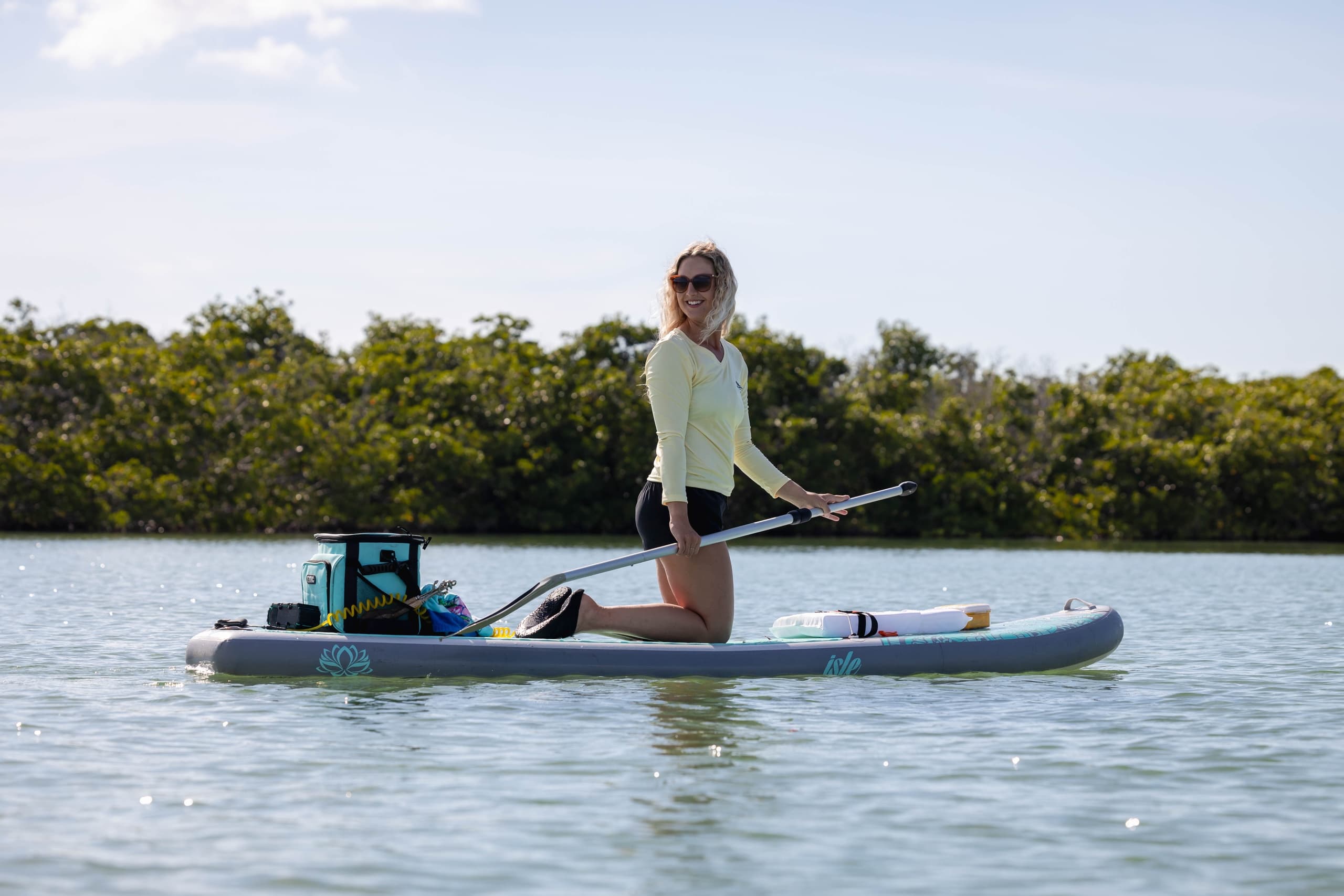 Woman paddleboarding on calm coastal waters near mangroves
