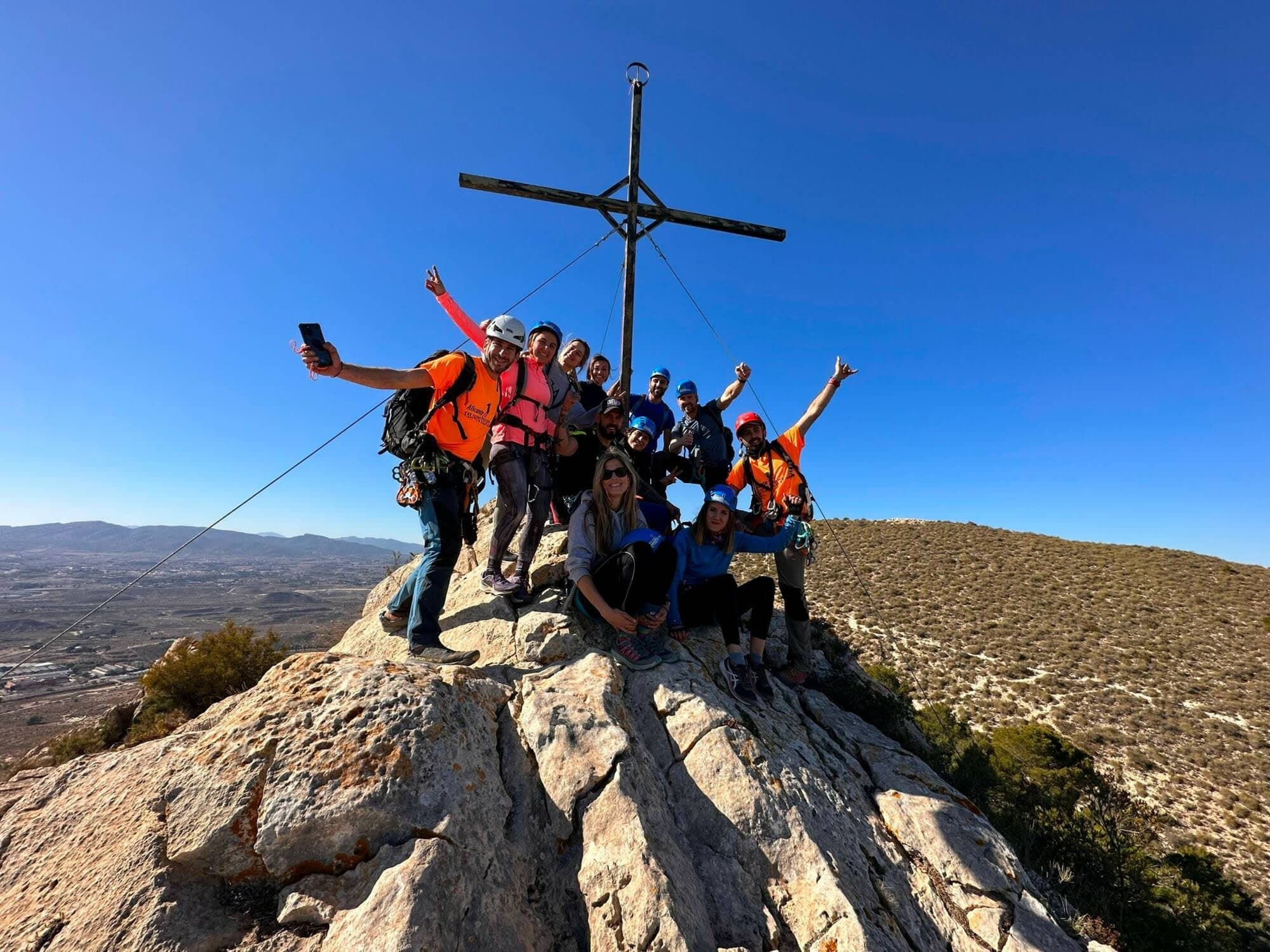 Hikers celebrating on mountain summit cross with clear sky view
