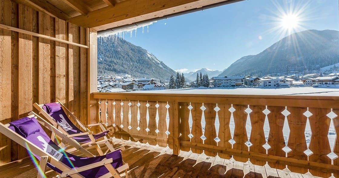 Balcony overlooking alpine mountains with deck chairs sunrise