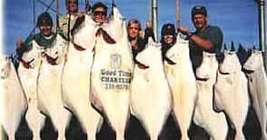 Anglers holding large halibut aboard charter fishing boat at sea