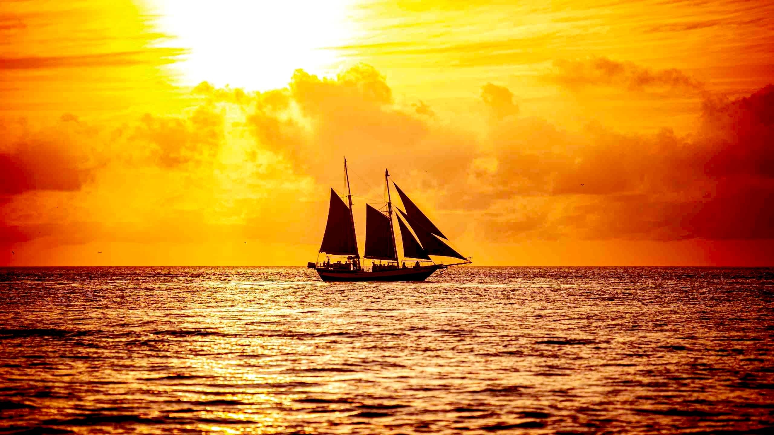Sailboat silhouetted against fiery sunset over the ocean