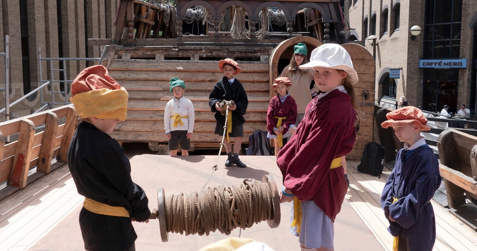 Kids roleplaying on historic wooden ship deck during tour