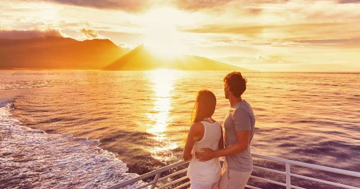 Couple watching sunset over ocean from cruise deck on voyage