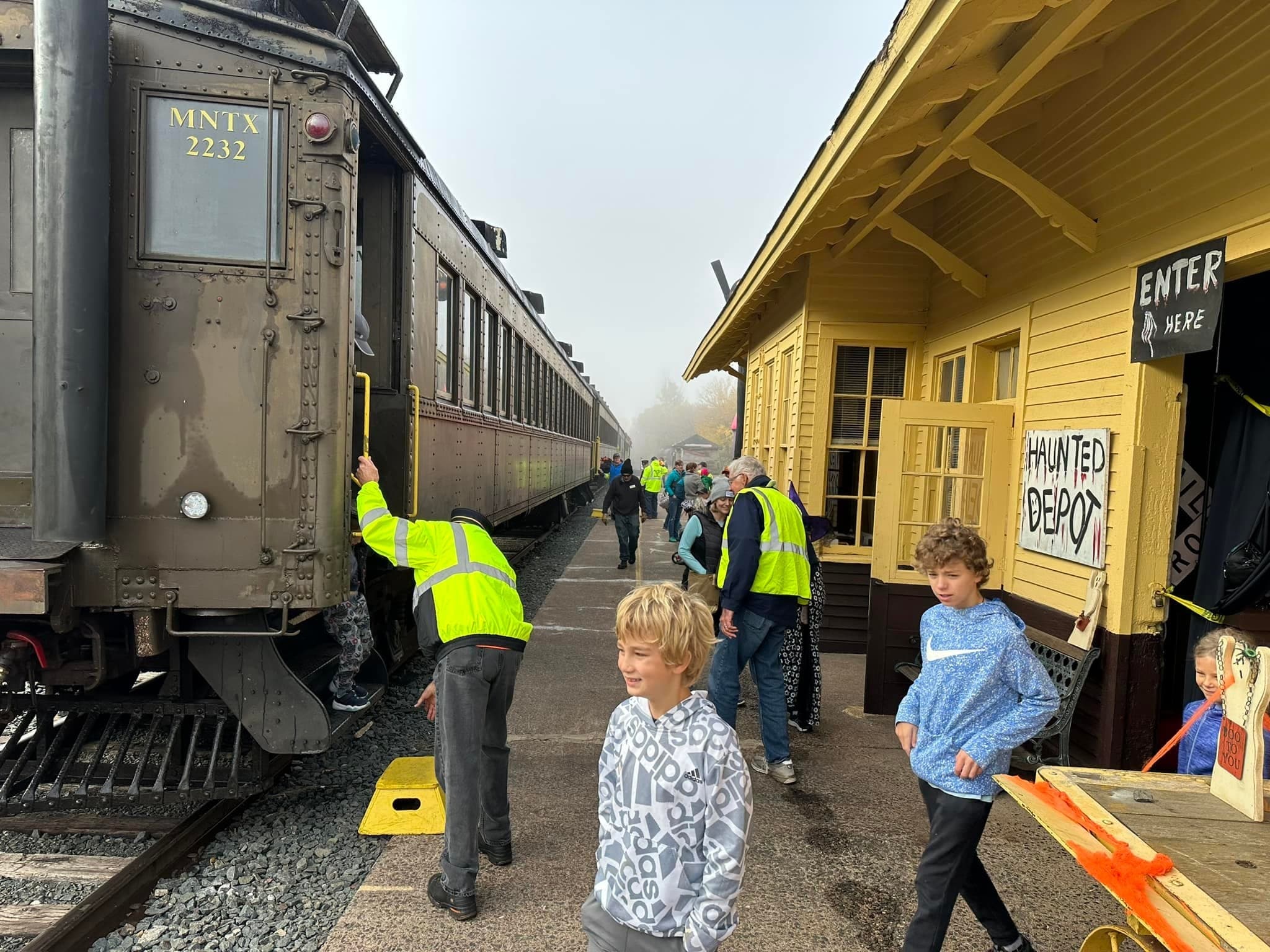 Families boarding vintage train at small outdoor station platform