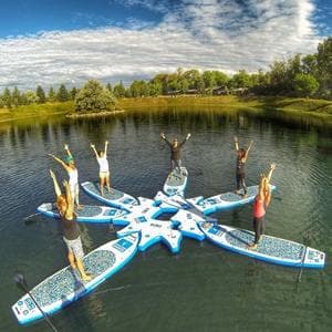 Stand-up paddleboarders forming star on tranquil lake, celebrating