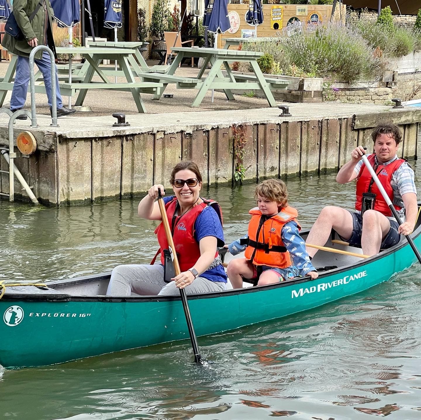 Family canoeing on tranquil river with lifejackets in Cotswolds