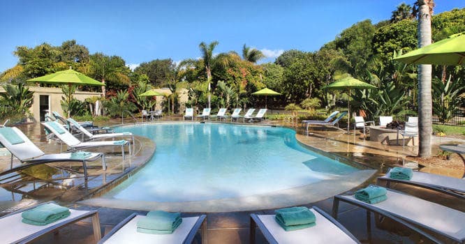 Panoramic coastal resort pool and loungers under blue sky