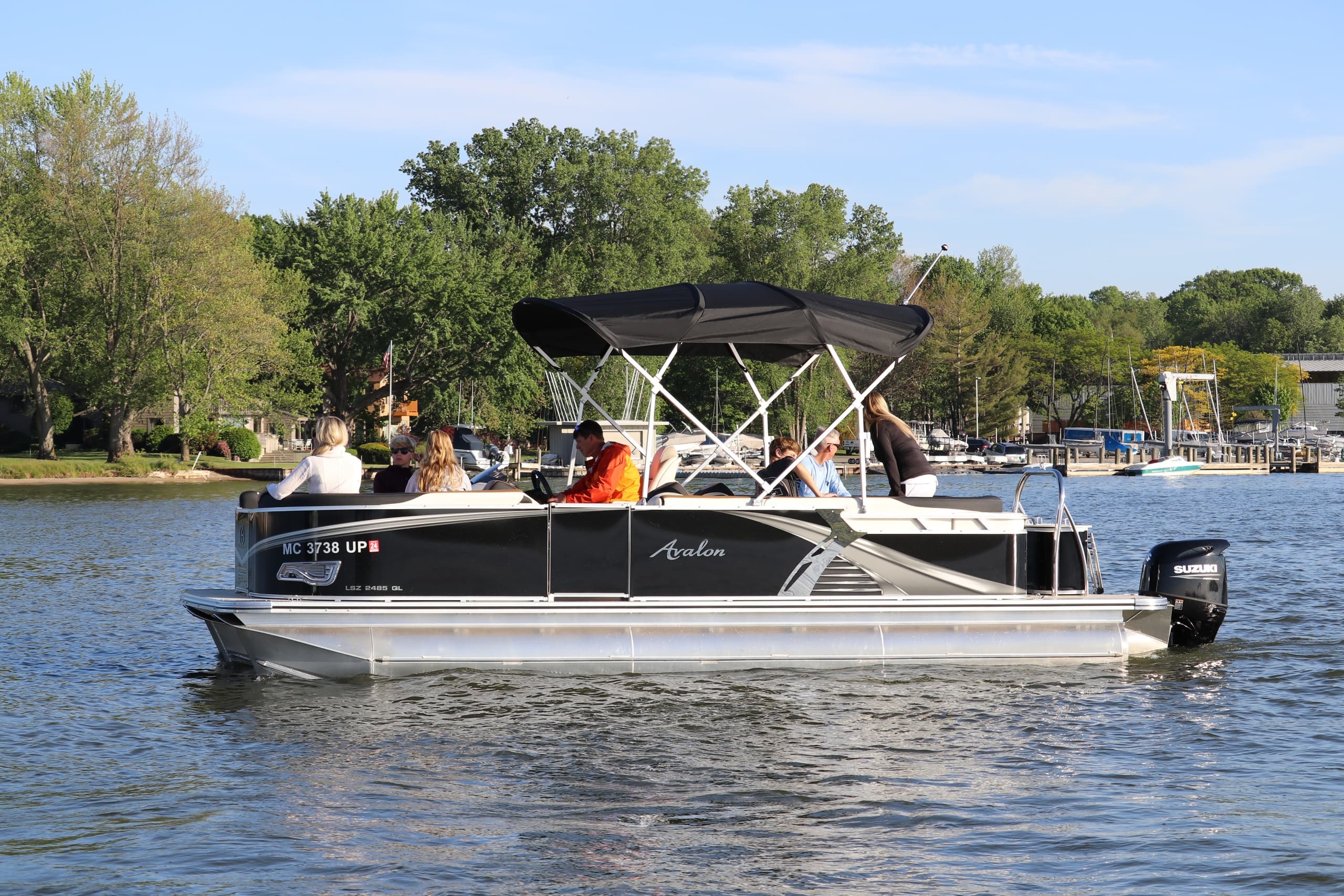 Pontoon boat cruising a calm lake with tree-lined shore