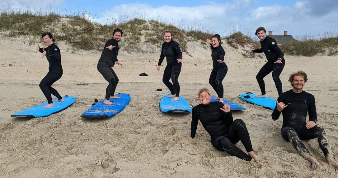 Group surf lesson on sandy beach with blue foam boards