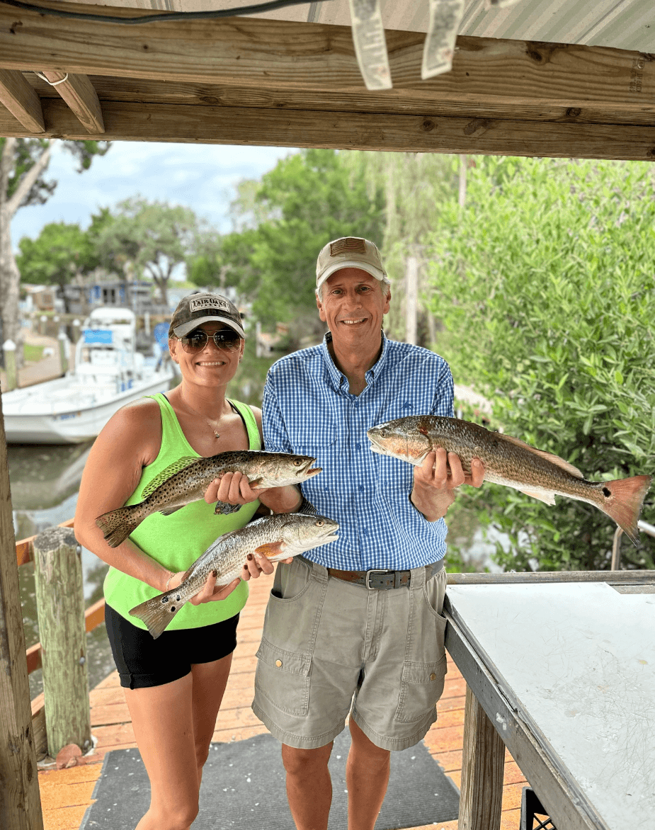 Anglers posing with speckled trout at marina after charter