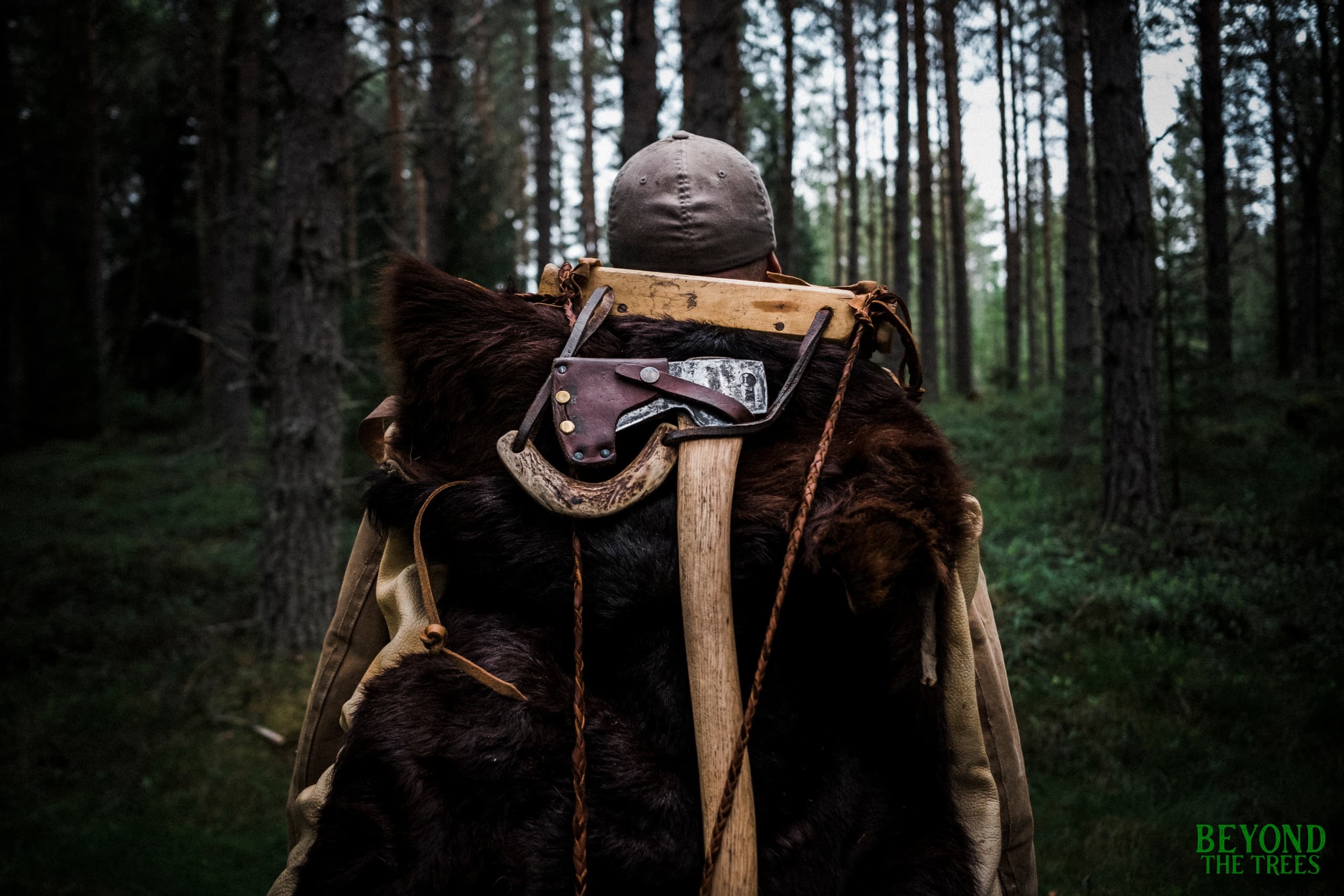 Backpacker with traditional fur pack trekking through boreal pine forest