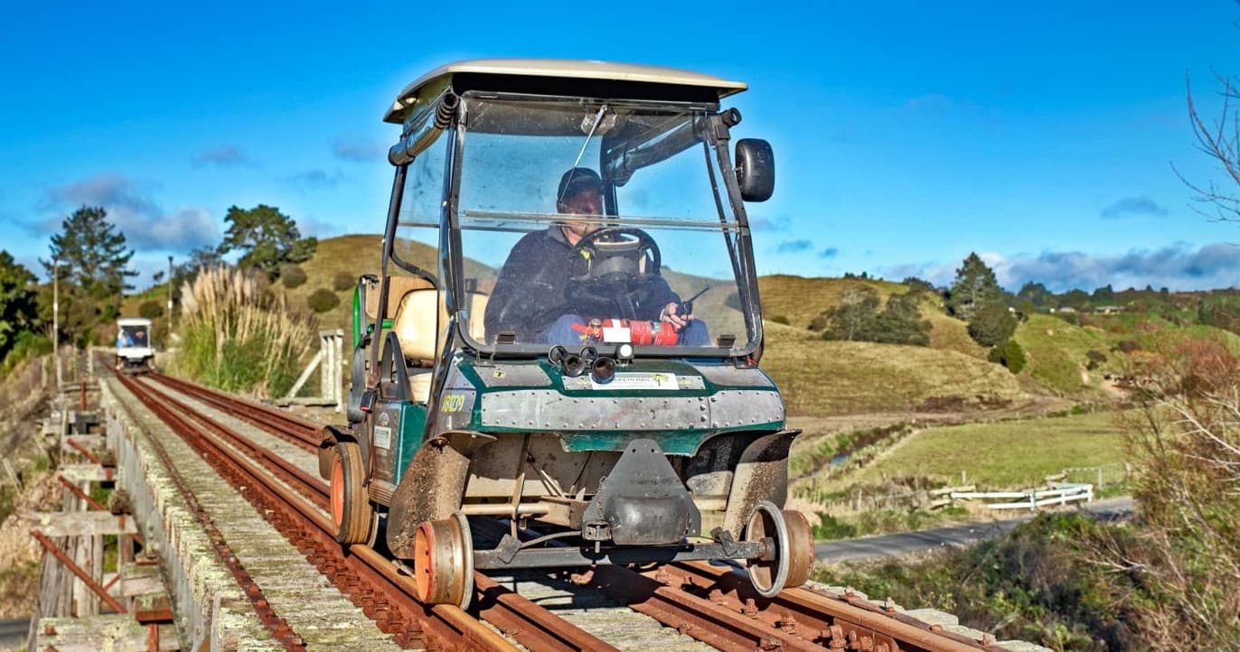 Rail speeder riding along rural bridge with rolling hills
