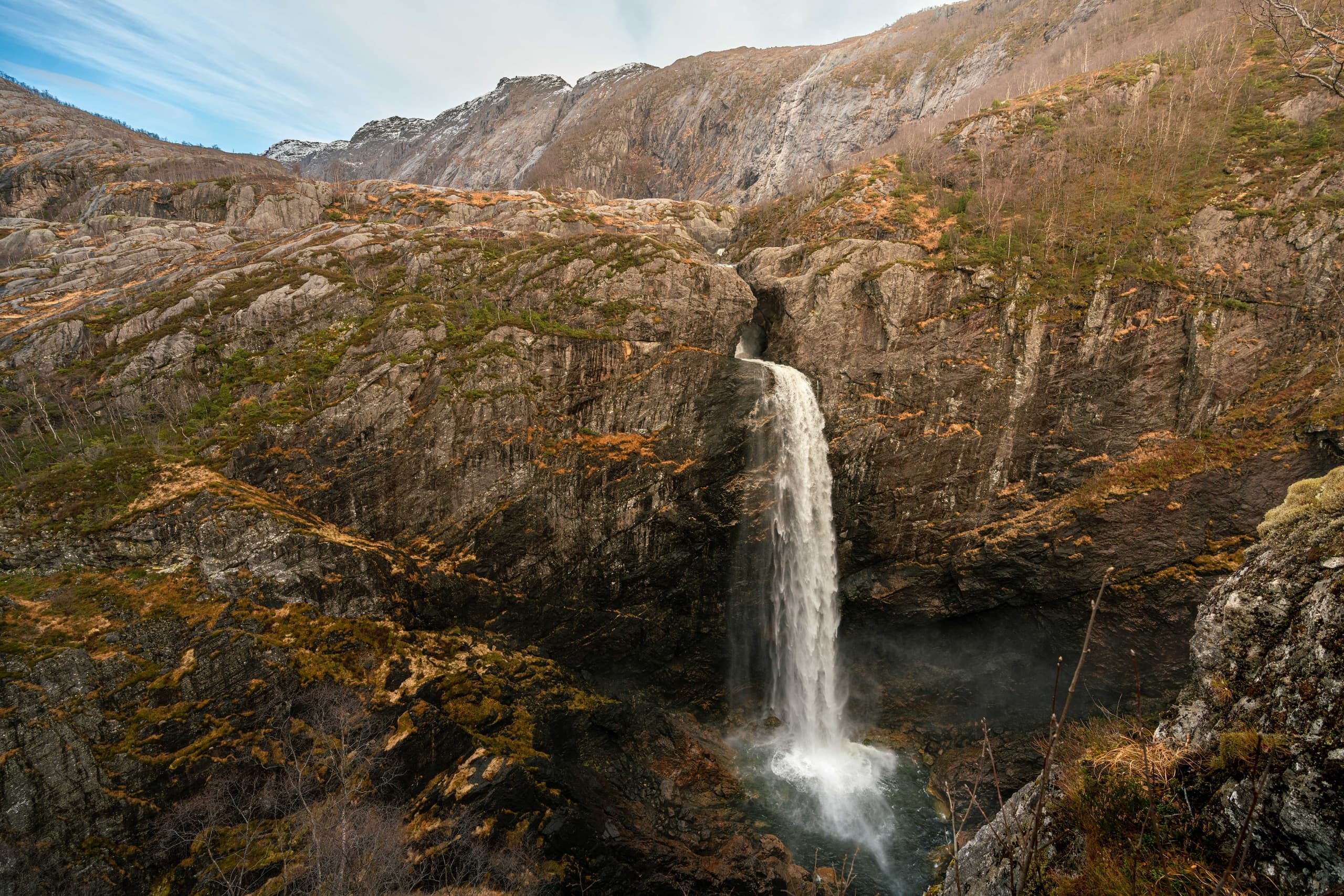 Waterfall cascading through rugged Norwegian mountain landscape
