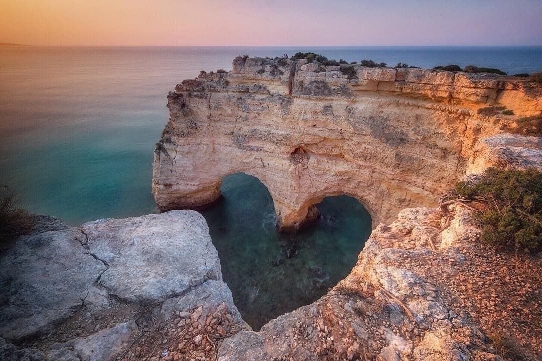 Clifftop heart-shaped sea arch at sunset, coastal viewpoint photo