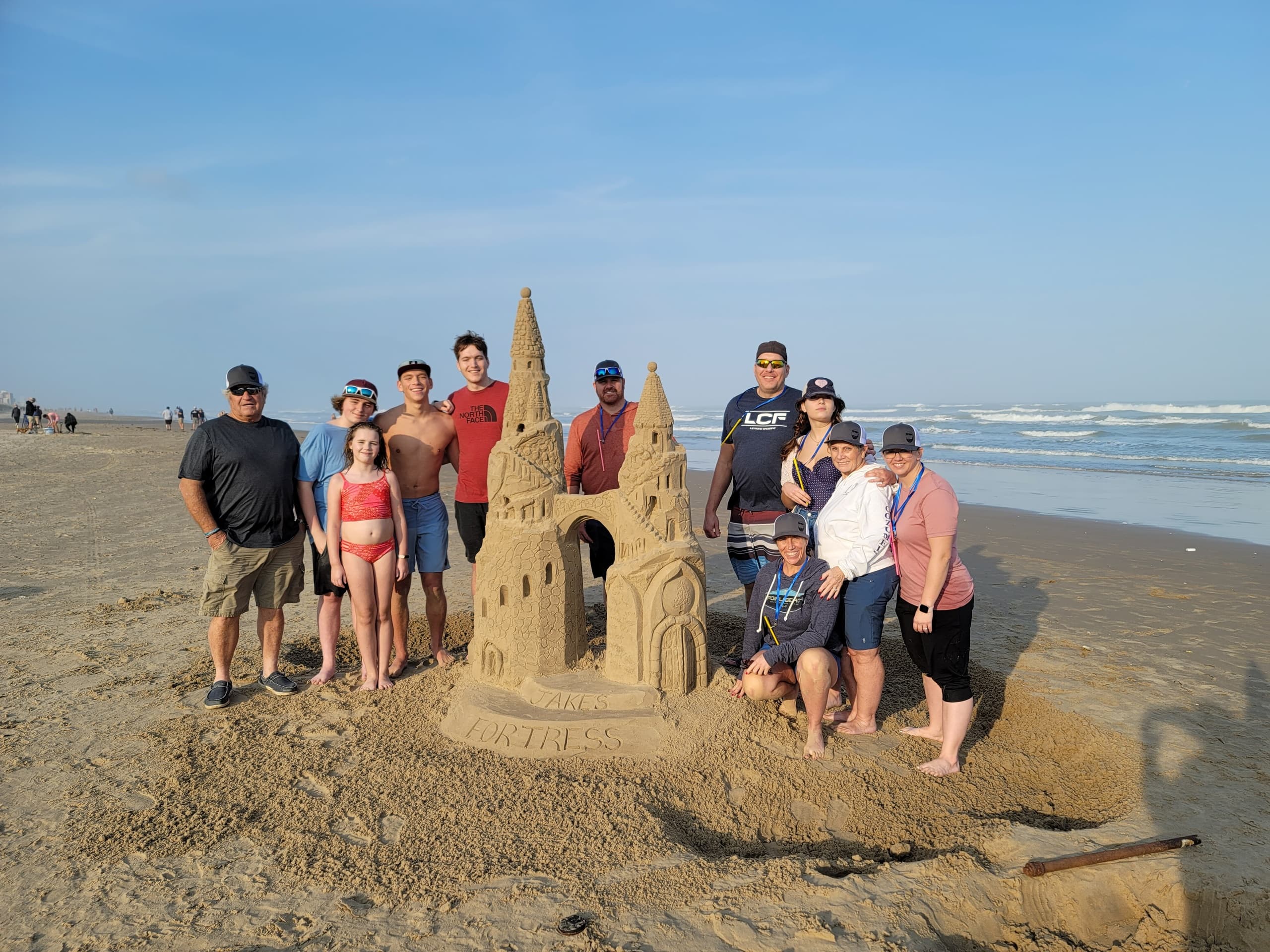 Group building large sandcastle on sunny Texas beach