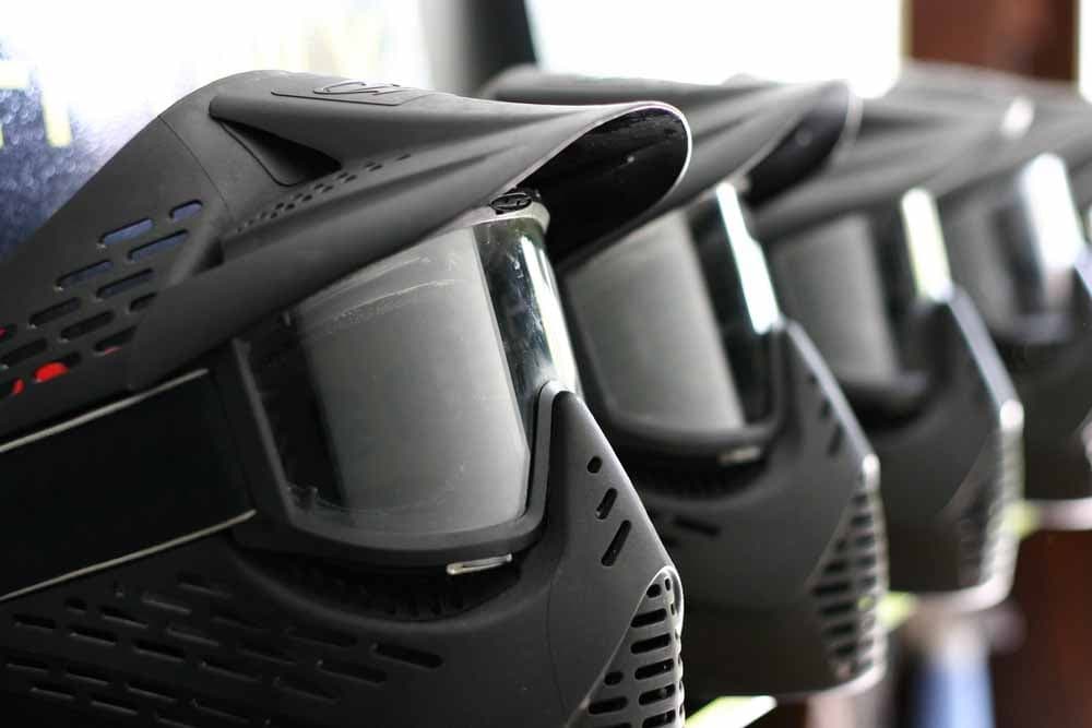 Line of black paintball masks and goggles ready for players