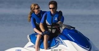 Couple riding blue jet ski on open water near coastline