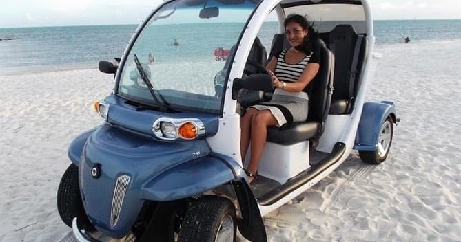 Passenger in electric island cart parked on sandy beach coastline