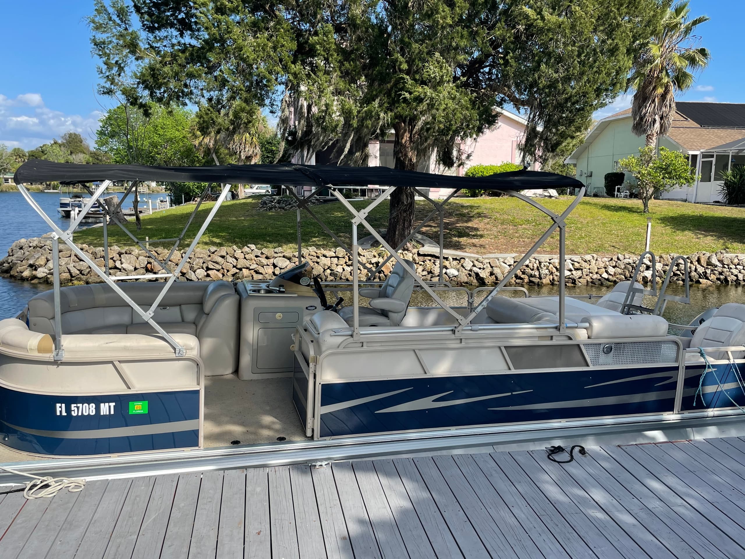 Pontoon boat docked at residential shoreline on a sunny day
