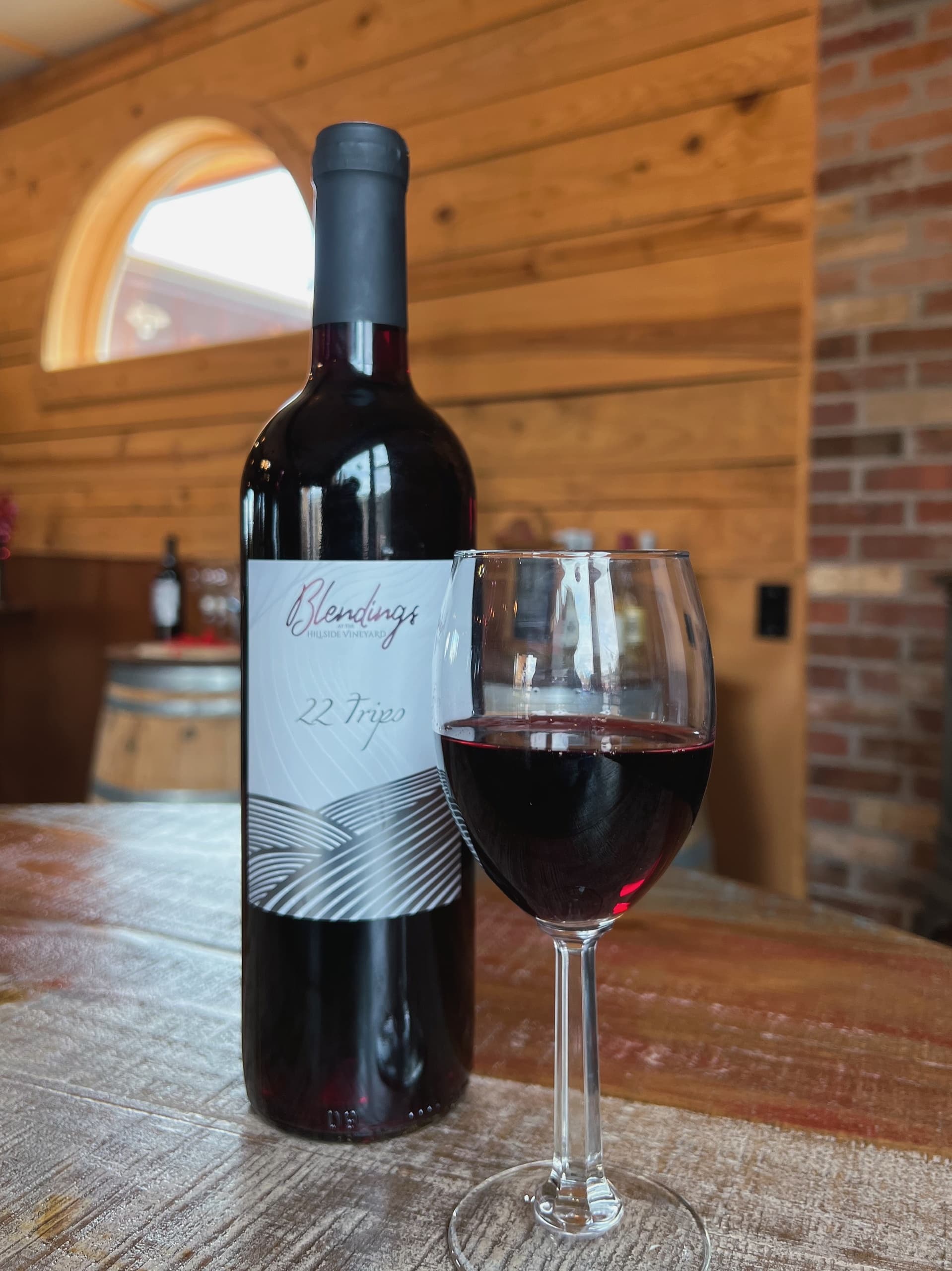 Bottle and poured red wine on rustic tasting room table