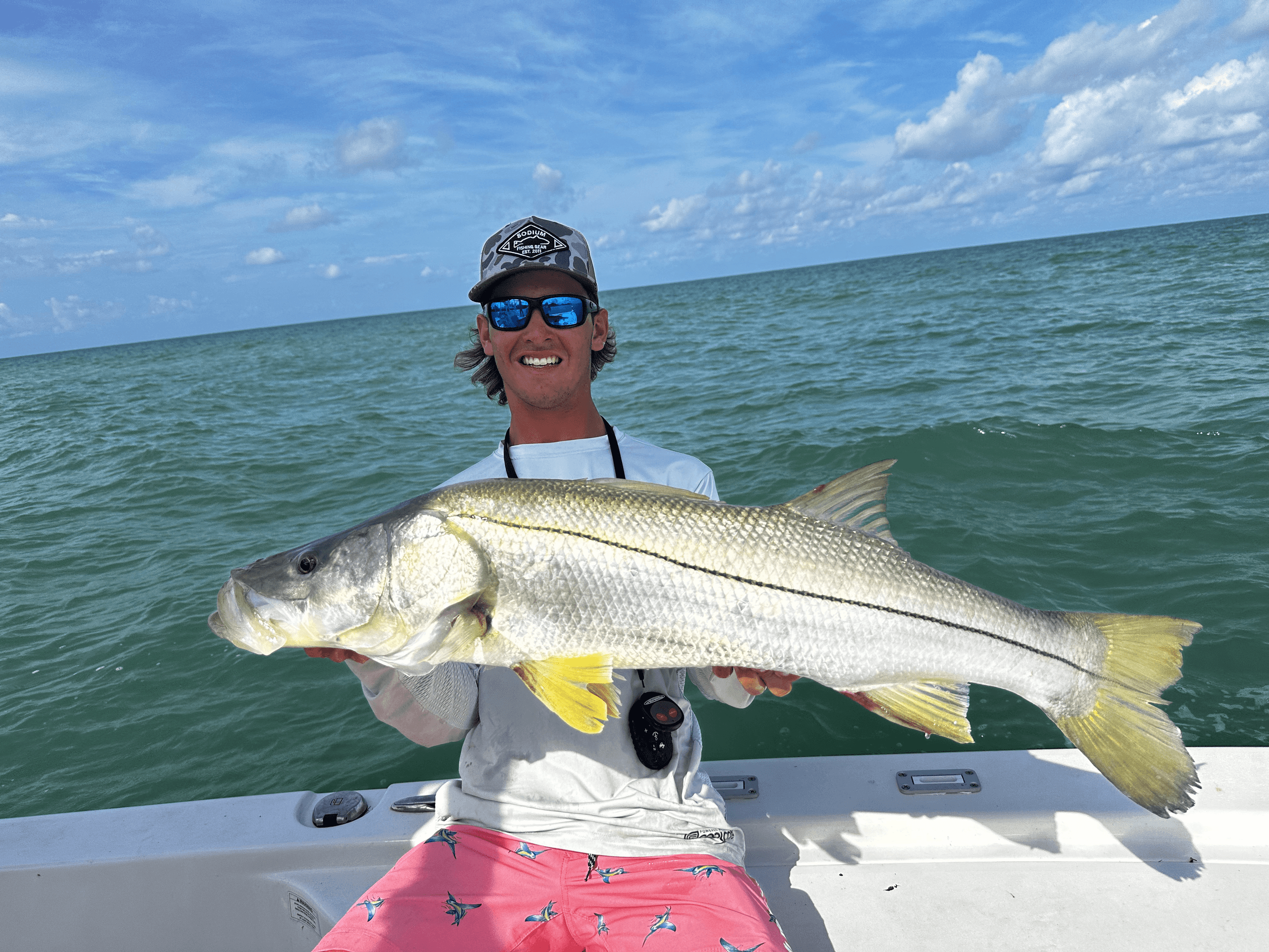 Angler holding large snook on shallow gulf waters