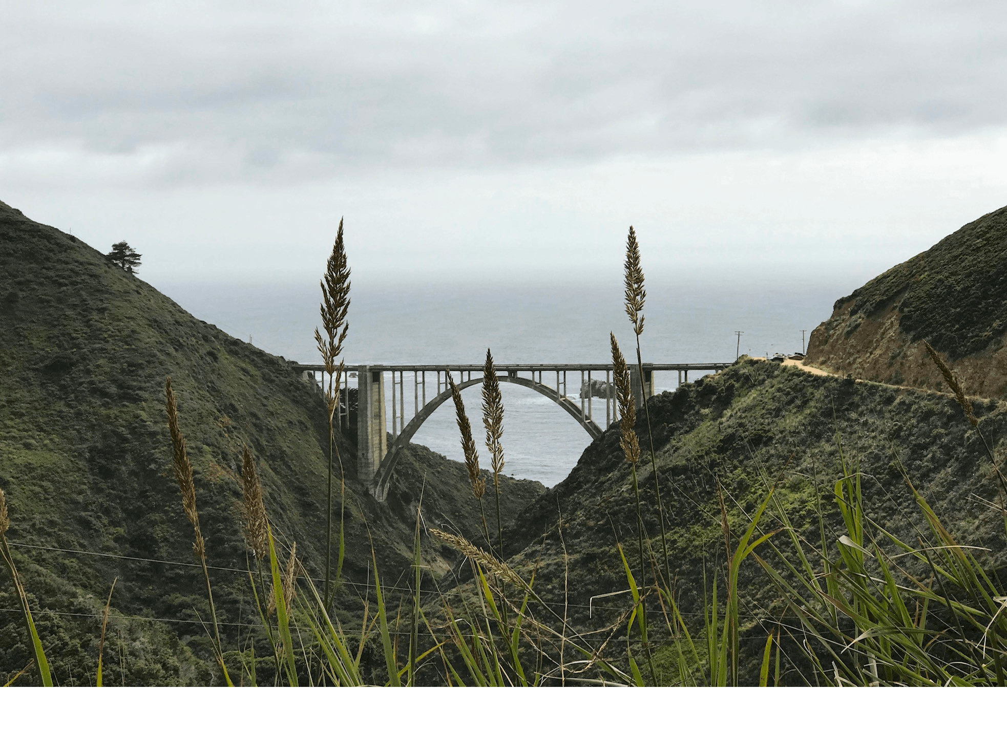 Iconic coastal arch bridge spanning rugged cliffs, scenic highway view