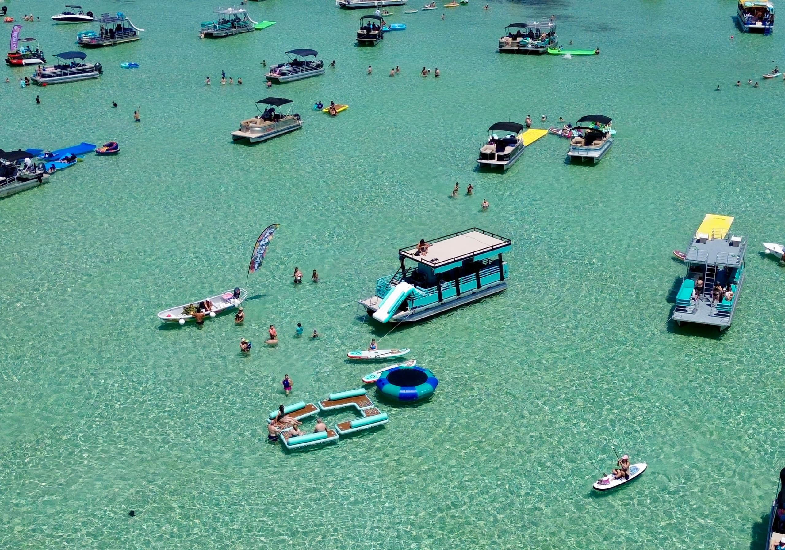 Cluster of party pontoons and swimmers in emerald shallows