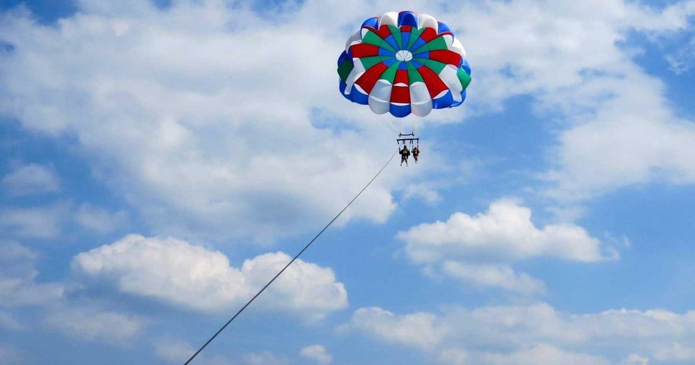 Two people parasailing against blue sky with puffy clouds