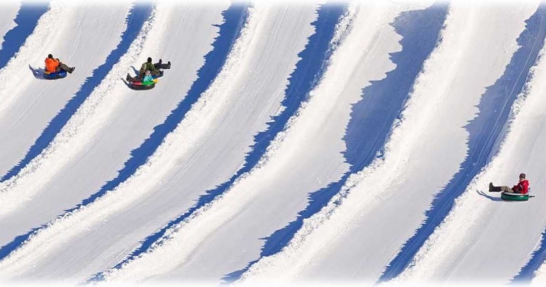 Snow tubing on groomed snowy lanes with riders sliding fast