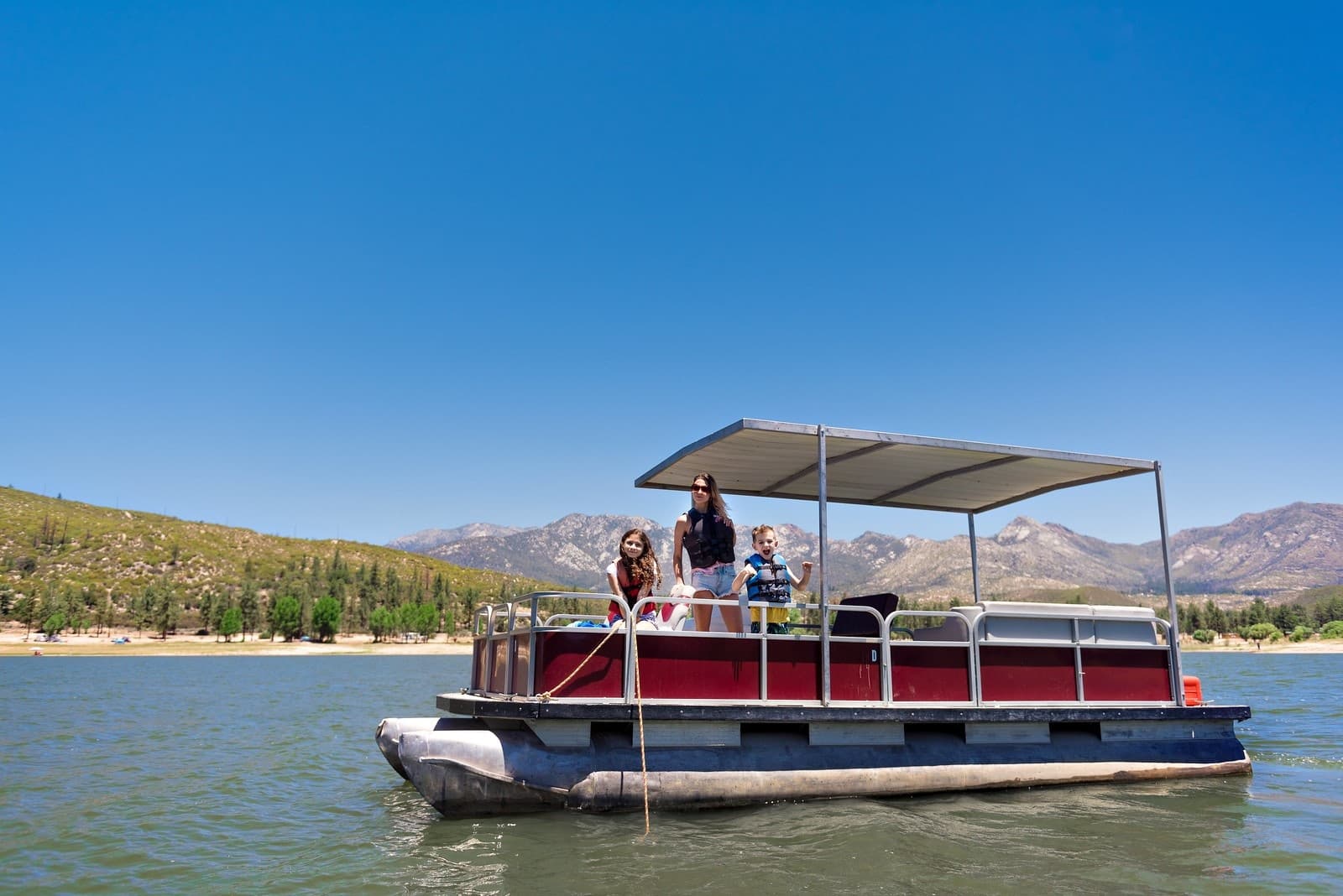 Pontoon boat cruising on sunny mountain lake, recreational boating