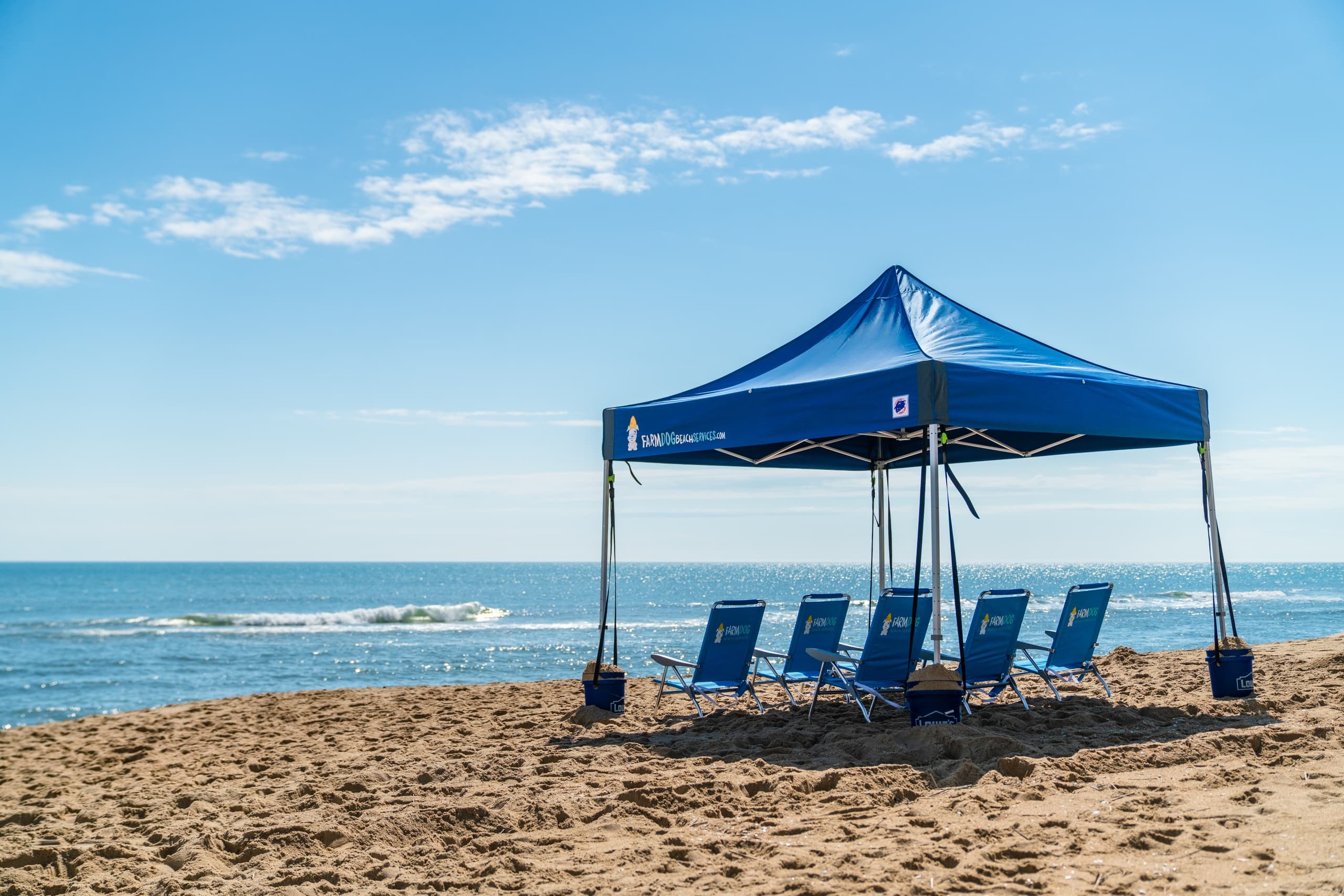 Blue beach canopy with lounge chairs on tranquil oceanfront sand