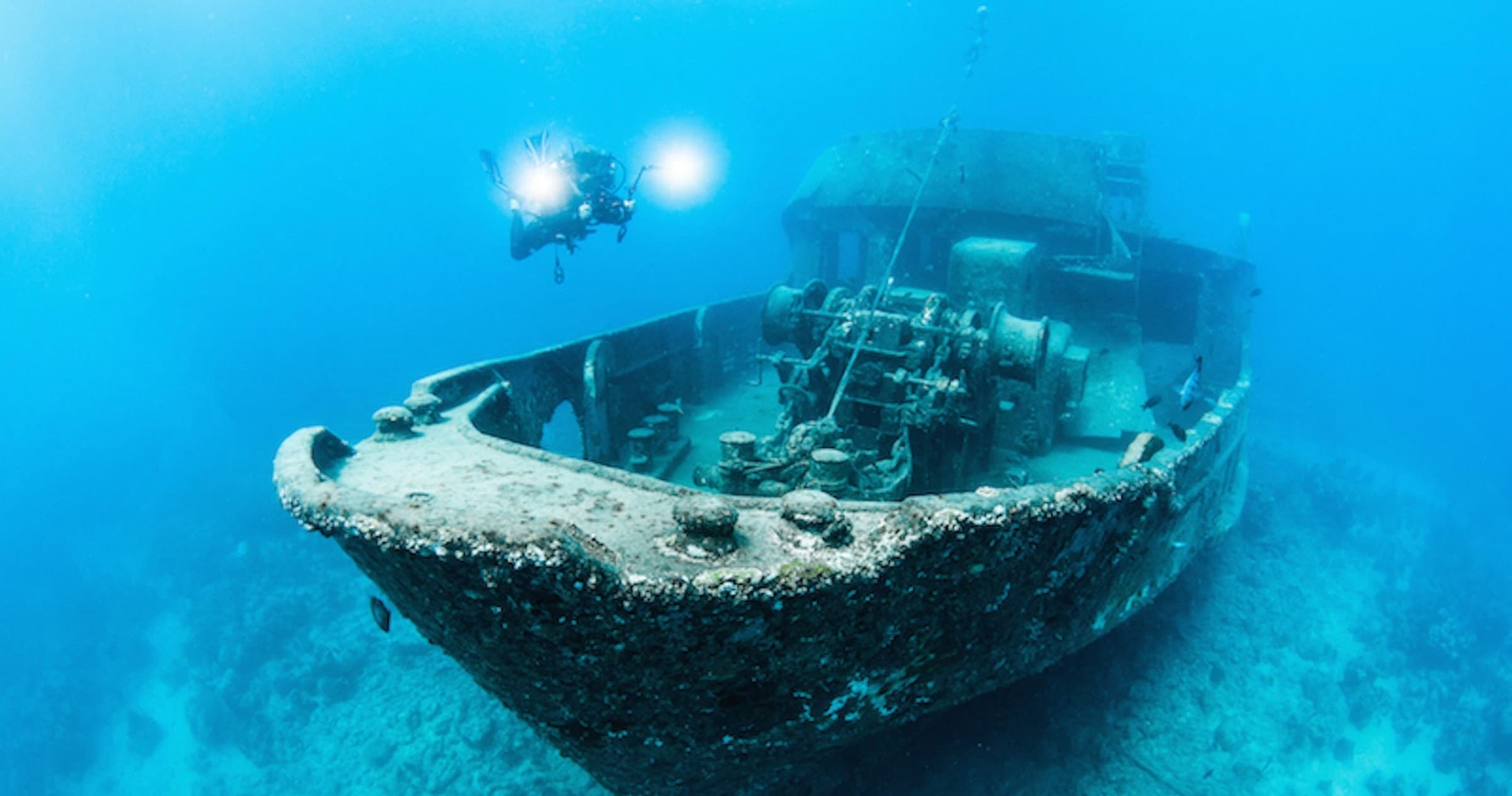 Sunken shipwreck on sandy seabed, clear blue water scuba dive