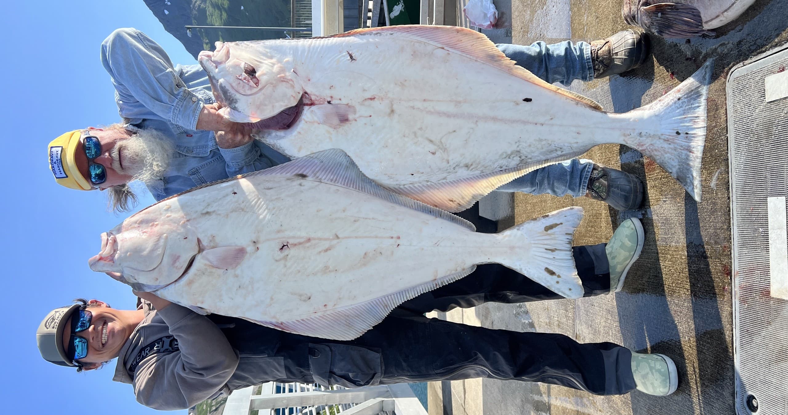 Anglers posing with giant halibut on Alaskan charter dock