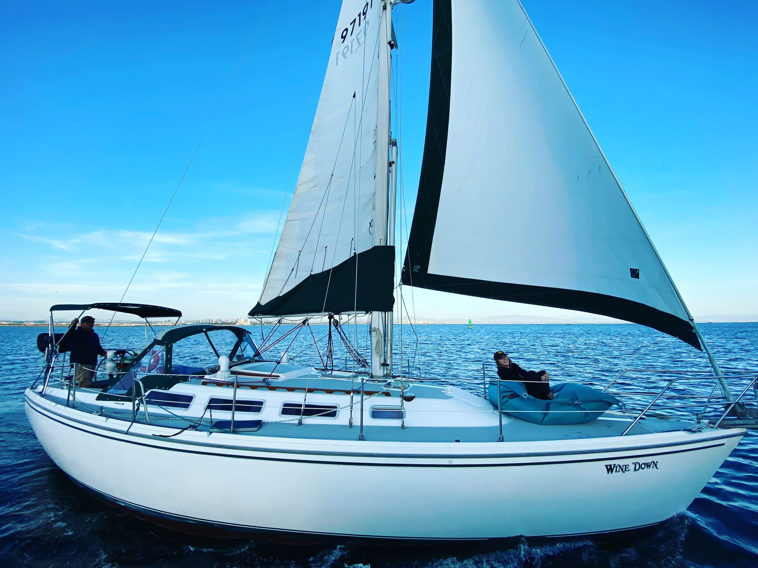 Sailboat cruising on open ocean with blue sky near coast