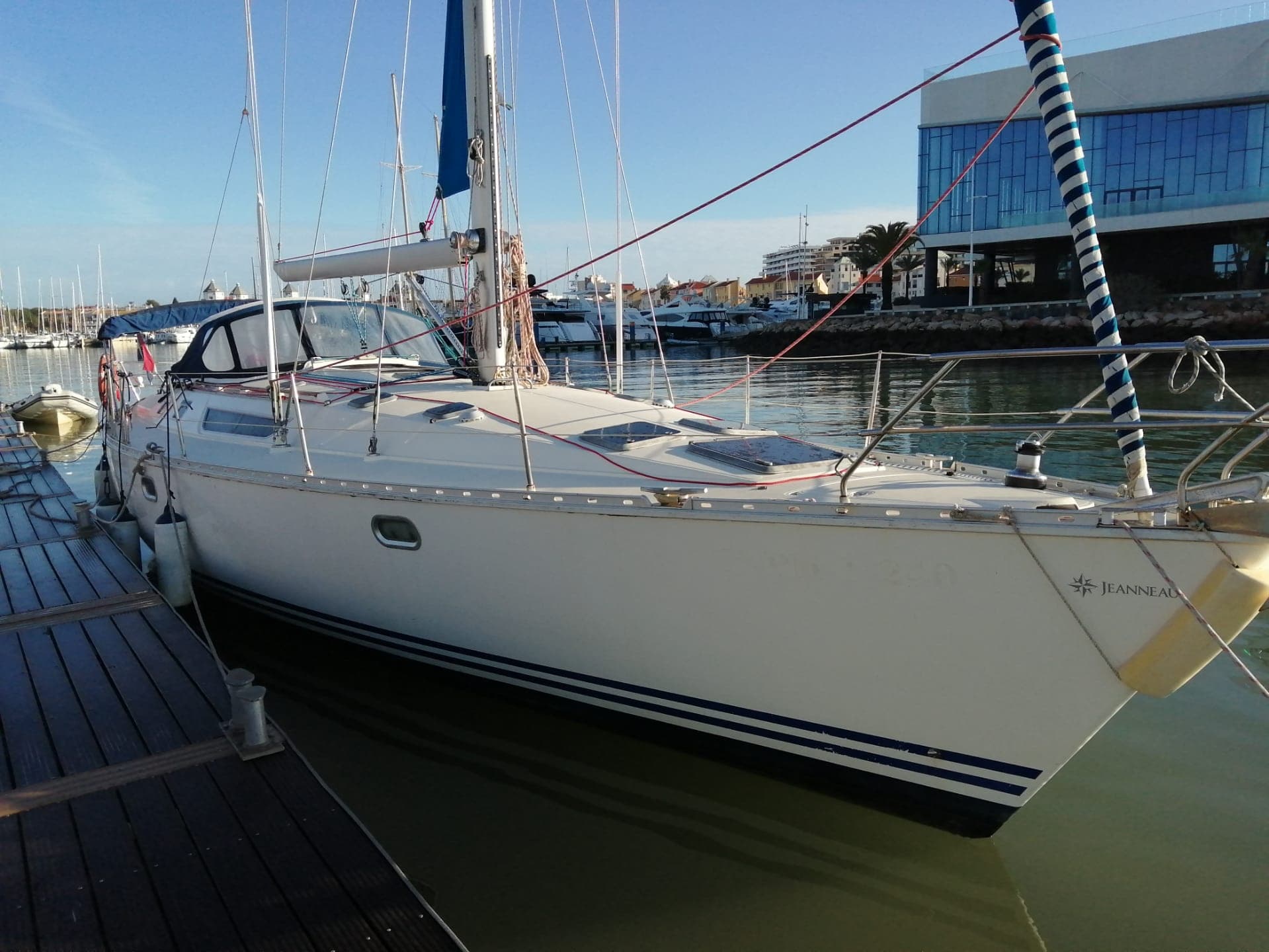 Docked white sailboat moored in marina at sunny harbor