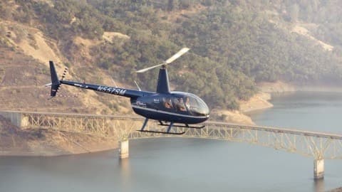 Helicopter scenic flight over lake and bridge at sunset