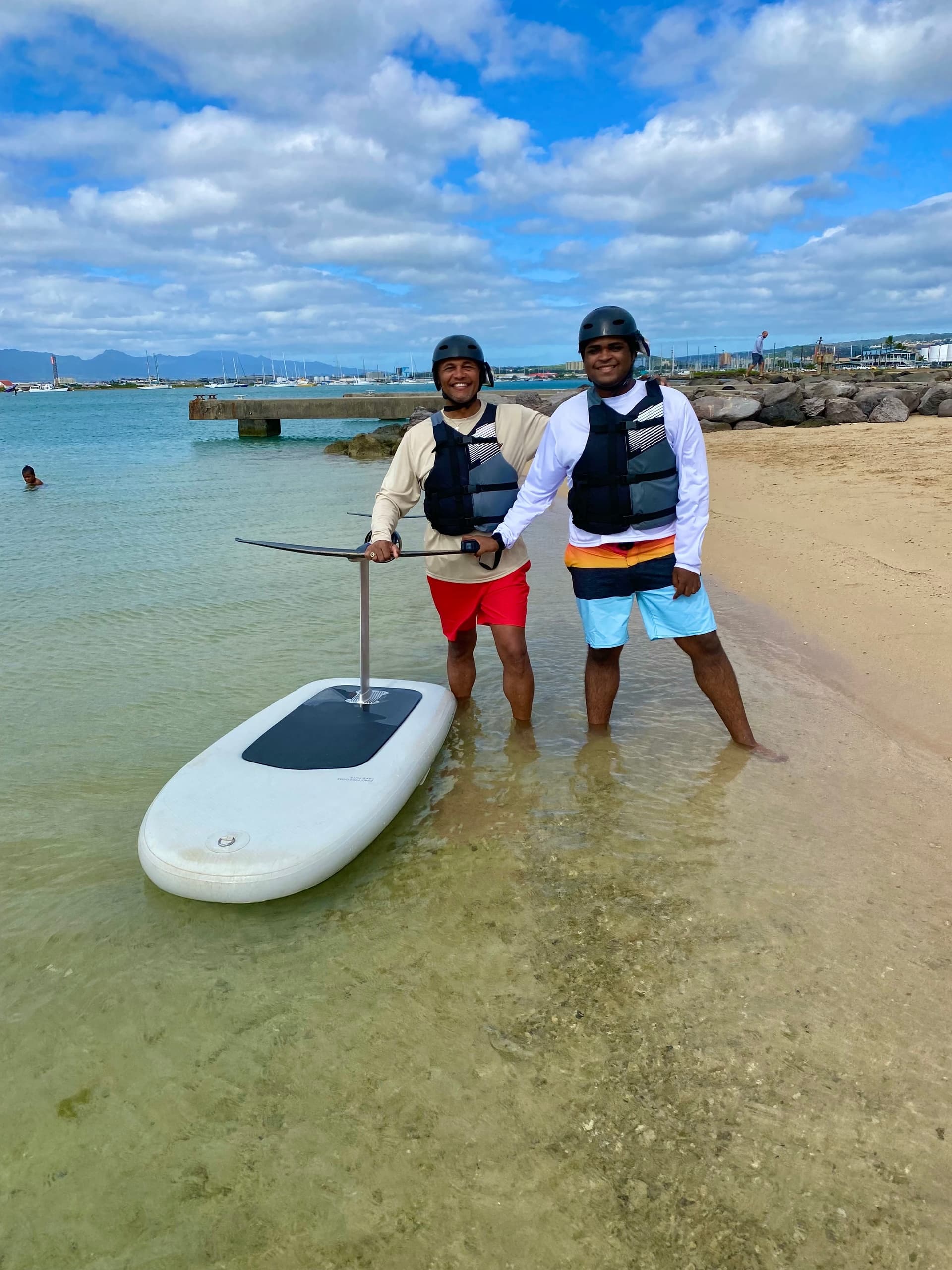 Two instructors with efoil board on shallow beach at Waikiki