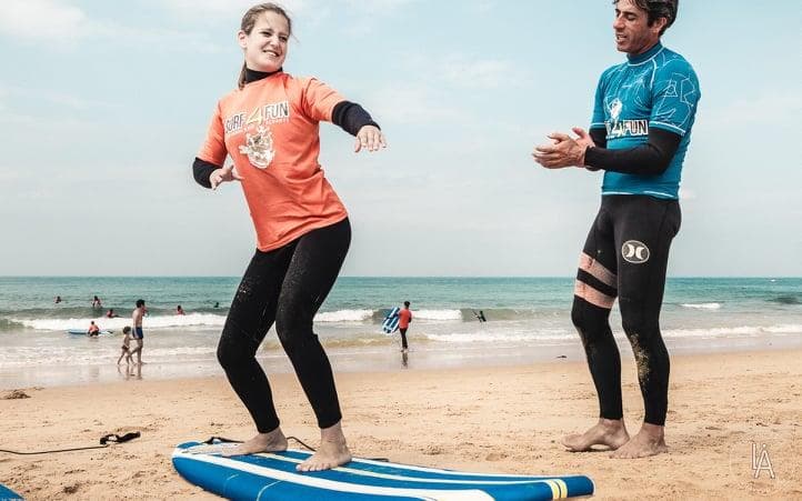 Surf lesson on sandy beach with instructor coaching beginner