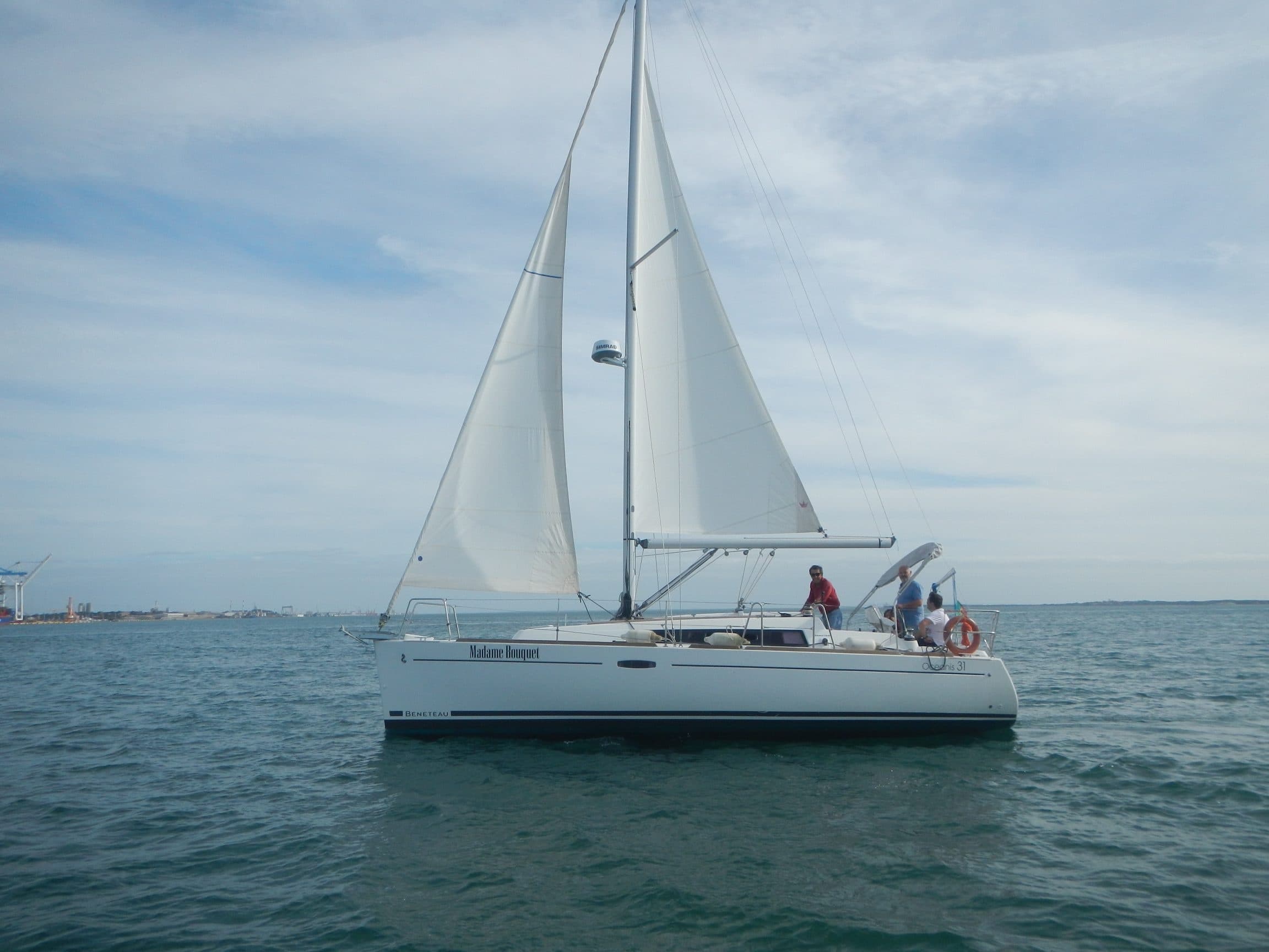 Sailboat cruising on open sea under cloudy blue sky