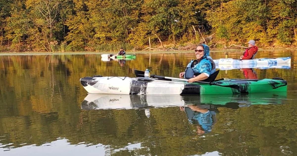 Group kayakers paddling on calm river near autumn shoreline