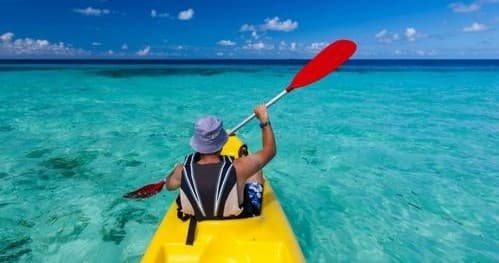 Kayaker paddling across clear turquoise tropical ocean waters