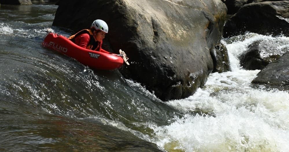 Whitewater kayaker navigating rocky river rapid in canyon